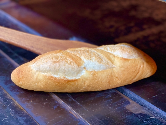 窯の中で焼き上がったフランスパンを木製のピールで取り出している様子